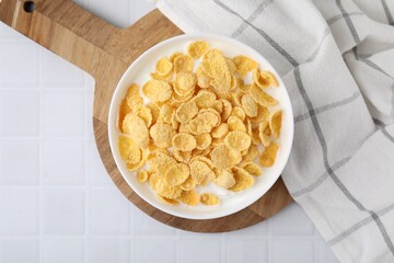 Breakfast cereal. Tasty corn flakes with milk in bowl on white tiled table, top view