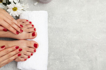 Woman with stylish red toenails after pedicure procedure and chamomile flowers on grey textured background top view. Space for text