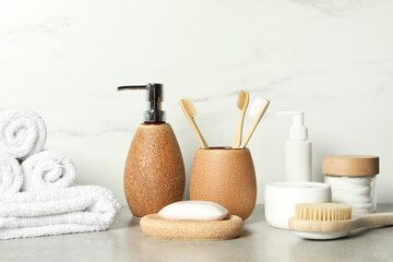 Different bath accessories and personal care products on gray table near white marble wall