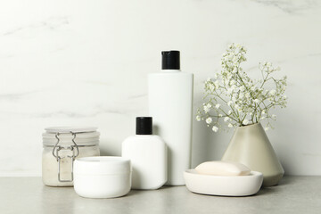 Bath accessories. Personal care products and gypsophila flowers in vase on gray table near white...
