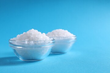 Natural salt and bowls on light blue background. Space for text