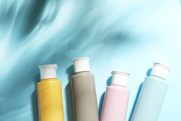 Cosmetic travel kit on light blue background, top view. Space for text