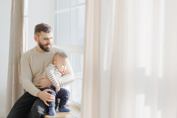 Father helps his little son see world outside window, lifestyle moment in life of fatherhood