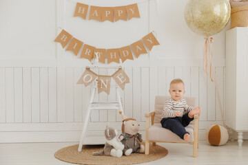 Naklejka premium Thoughtful setup for baby first birthday, featuring decorative banners and little boy with his plush toy, marks momentous occasion