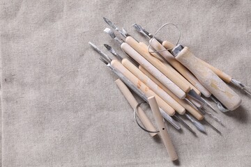 Set of different clay crafting tools on grey fabric, top view. Space for text