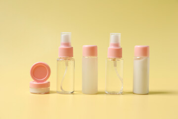 Cosmetic travel kit. Small containers of personal care products on yellow background