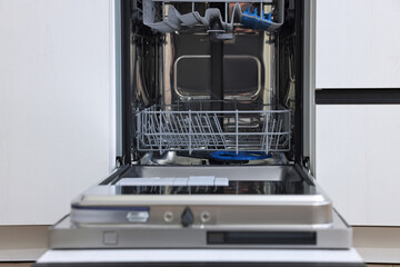 Open clean empty dishwasher in kitchen. Home appliance