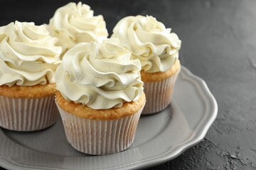 Tasty cupcakes with vanilla cream on black table, closeup