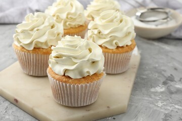 Tasty cupcakes with vanilla cream on grey table, closeup