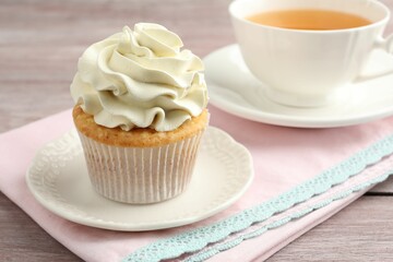 Obraz na płótnie Canvas Tasty cupcake with vanilla cream on pink wooden table, closeup