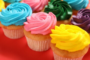 Delicious cupcakes with bright cream on red background, closeup