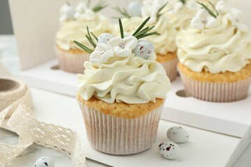 Tasty Easter cupcakes with vanilla cream on table, closeup