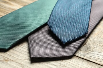 Different neckties on light wooden table, closeup