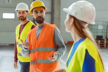Smiling happy bearded man and attractive woman wearing hard hat and work wear, vest talking