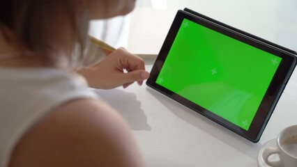 Woman working with tablet with green screen on