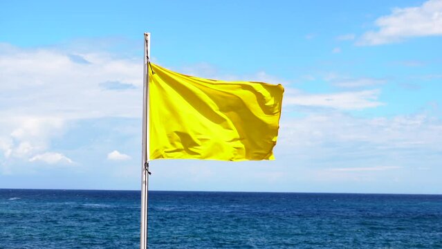 Yellow flag on the beach in summer summer, lifeguards sign to bathe carefully