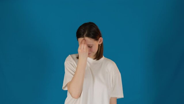 Frustrated female student claps fingers on forehead expressing self-reprimand. Lady uses facepalm gesture regretting about exam