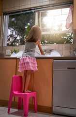 Girl, chair and washing dishes in kitchen, chore and helping to clean for hygiene or disinfect...