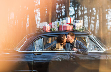Couple kissing in vintage car with presents on roof