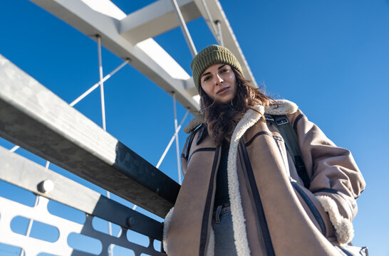 Young fashionable woman in ghetto urban street style wardrobe on the street. Different look female with cool attitude outdoor posing in hobo clothes.