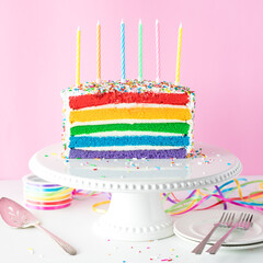 A rainbow birthday cake with unlit candles, ready for a celebration.