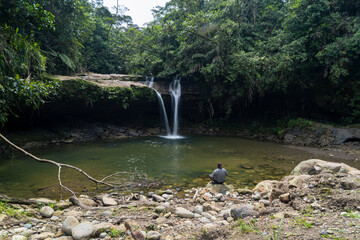 Man sitting in front of a waterfall