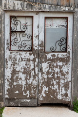 A pair of weathered, peeling white painted doors to a storage shed on an Israeli kibbutz.