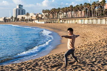 Asian Man practicing yoga on the beach
