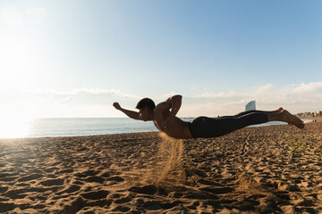 Man doing superman pose in beach sand