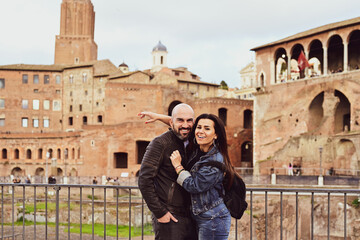 Happy  Beautiful Tourists  couple traveling at Rome, Italy,  near Ancient Trajan's Market, ruins in...