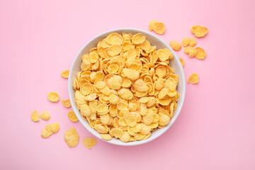 Breakfast cereal. Tasty corn flakes in bowl on pink table, top view