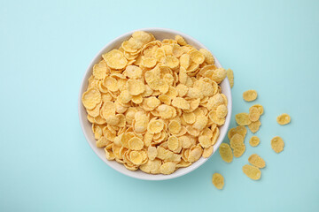 Breakfast cereal. Tasty corn flakes in bowl on light blue table, top view