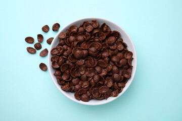 Breakfast cereal. Chocolate corn flakes in bowl on light blue table, top view