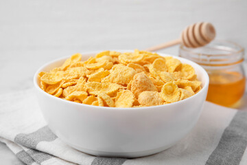 Tasty crispy corn flakes in bowl on table, closeup. Breakfast cereal