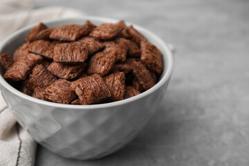 Chocolate cereal pads in bowl on grey table, closeup. Space for text