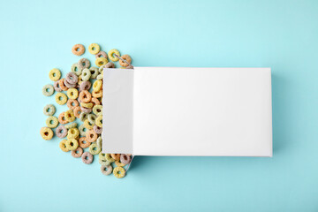 Paper box with tasty cereal rings on light blue background, flat lay