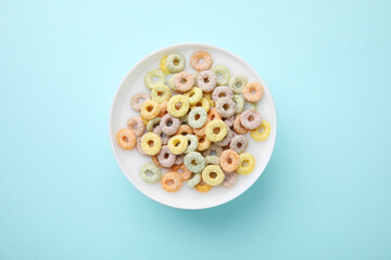Tasty colorful cereal rings and milk in bowl on turquoise background, top view © New Africa