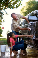 Father, girl and car washing for cleaning, learning responsibility and development outdoor. Child,...