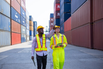 Asian and black engineers check cargo at shipping container