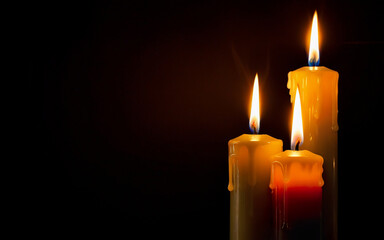 yellow burning wax candles on a black background with space for text
