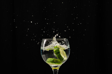 A band of lemon falling into a wine glass with water. Splash effect.
