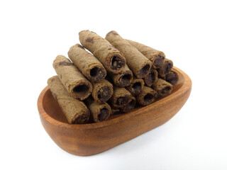 Chocolate wafers rolled in a wooden bowl isolated on white background. A delicious snack that tastes sweet and crunchy.