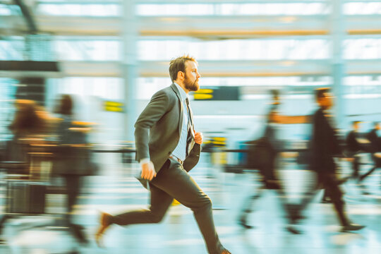 Handsome businessman rushing in airport to catch a flight with blurry people around him.