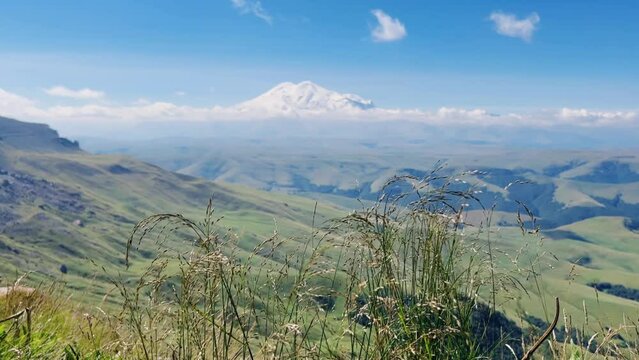 View of Elbrus from the Bermamyt plateau. Caucasus 2023. A trip to Bermamyt, the Grand Canyon in Russia. Mountain landscape on a summer day. Blue sky of Karachay-Cherkessia. Caucasian Ridge 4K