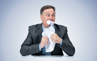 A frightened official in a dark suit eats the evidence paper, on a light blue background. The concept of document destruction