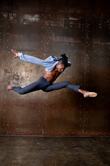 Energetic Afro American male dancer jumps and twirls in a studio, executing pirouettes with grace....