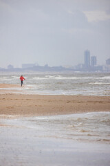 Obraz premium A beautiful walk by the sea. Magnificent sandy beach. Strong waves and various city buildings in the background. Blue and yellow colors of the North Sea.