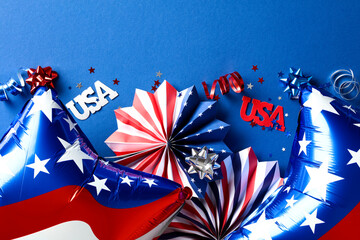 4th of July Independence Day decorations and American flag color balloons on dark blue background. Flat lay, top view