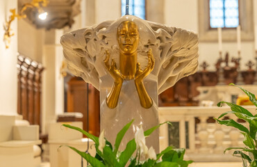 Close-up on golden face and hands of strange sculpture used as ornament inside an italian church