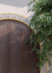 Front gate of Taiwanese temple, The traditional wooden arched door on white brick wall and bamboo leaves at Fo Guang Shan Thaihua Temple. Taiwanese temple style, Space for text, Selective focus.